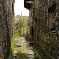 Narrow cobblestone lane between traditional stone houses.