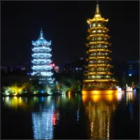 The illuminated Sun and Moon Pagodas reflected in Shan Lake after dark.