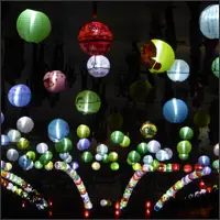 Hand-painted lanterns hanging above a pedestrian street during an evening festival.
