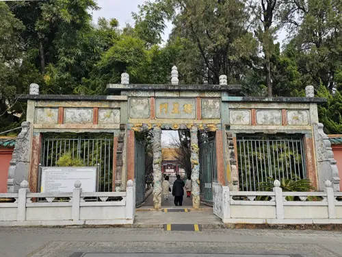 Weathered stone and wooden entrance gate of Wenmiao seen from the street, modest and slightly worn.