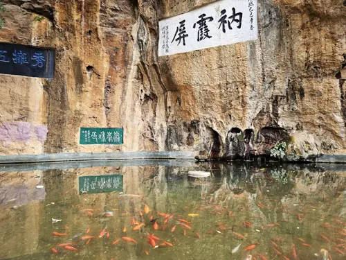 Rear pond at Yuantong Temple reflecting stone walls and textured rock surface, with water gently rippling.