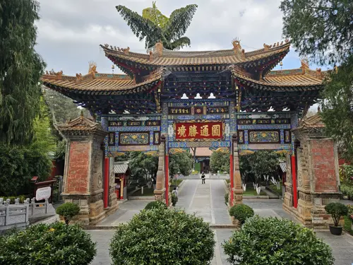 Large decorated entrance gate inside Yuantong Temple park in Kunming, with traditional Chinese architectural details.