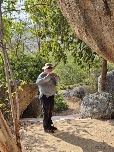 Man taking a photo near mosaic tiles and large boulders at Wat Khao Hin Thoen
